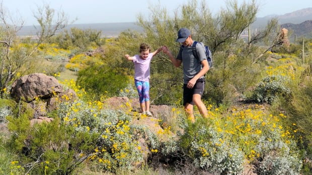 father helping daughter on hike