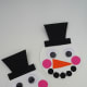 Create the hat by cutting a square and rectangle from black cardstock. Assemble the snowman’s hat by gluing the rim (rectangle) to the bottom of the main hat piece (square). Now glue the hat to the snowman’s head.