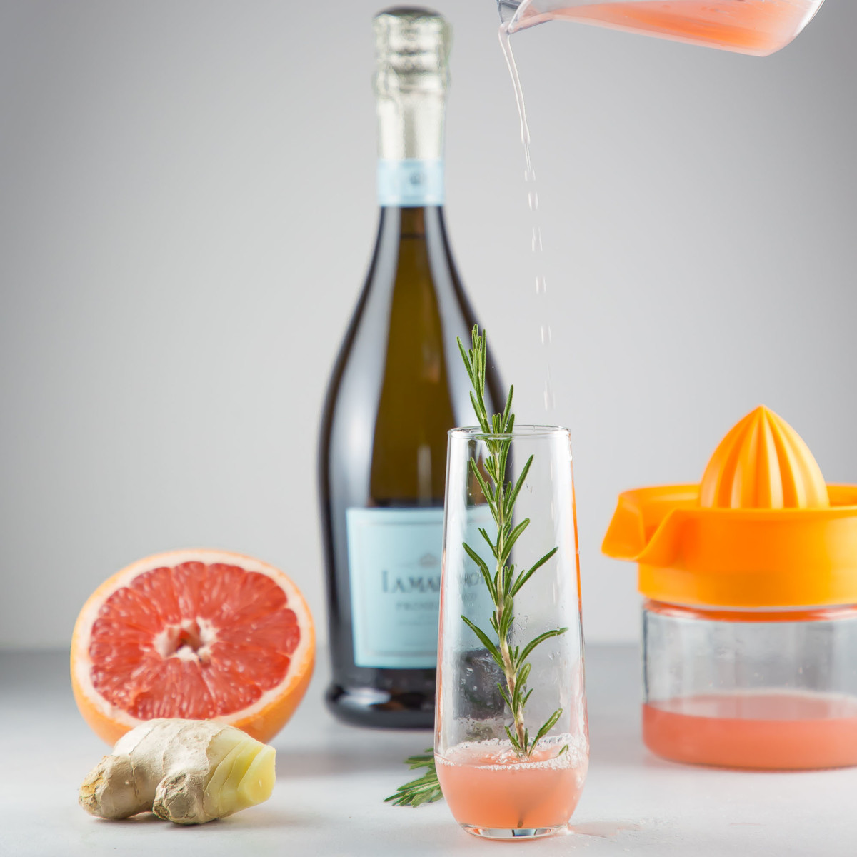 Grapefruit juice pouring into flute for grapefruit prosecco cocktail