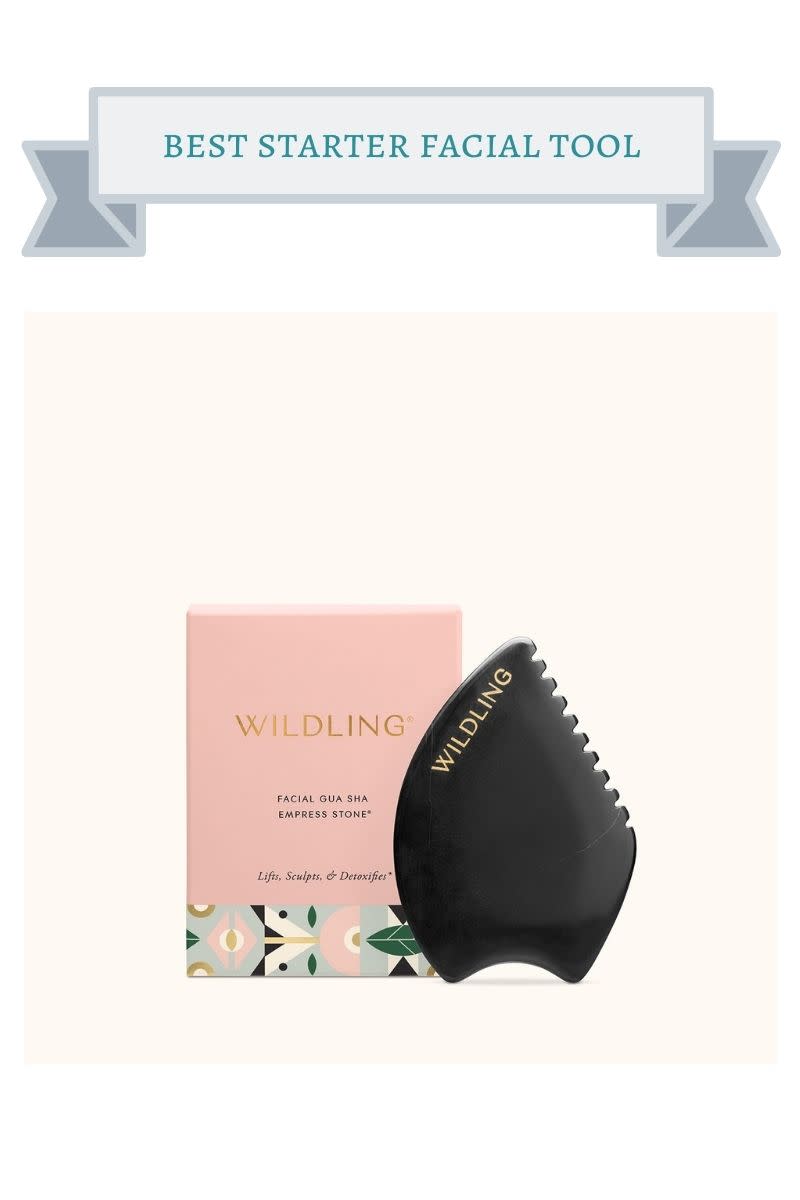 pink wildling box with blue, black, gold and green print behind black gua sha tool