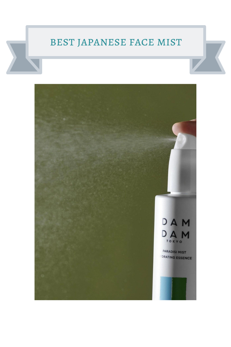 finger spraying white bottle of dam dam face mist with blue and green rectangles that make up a square on it